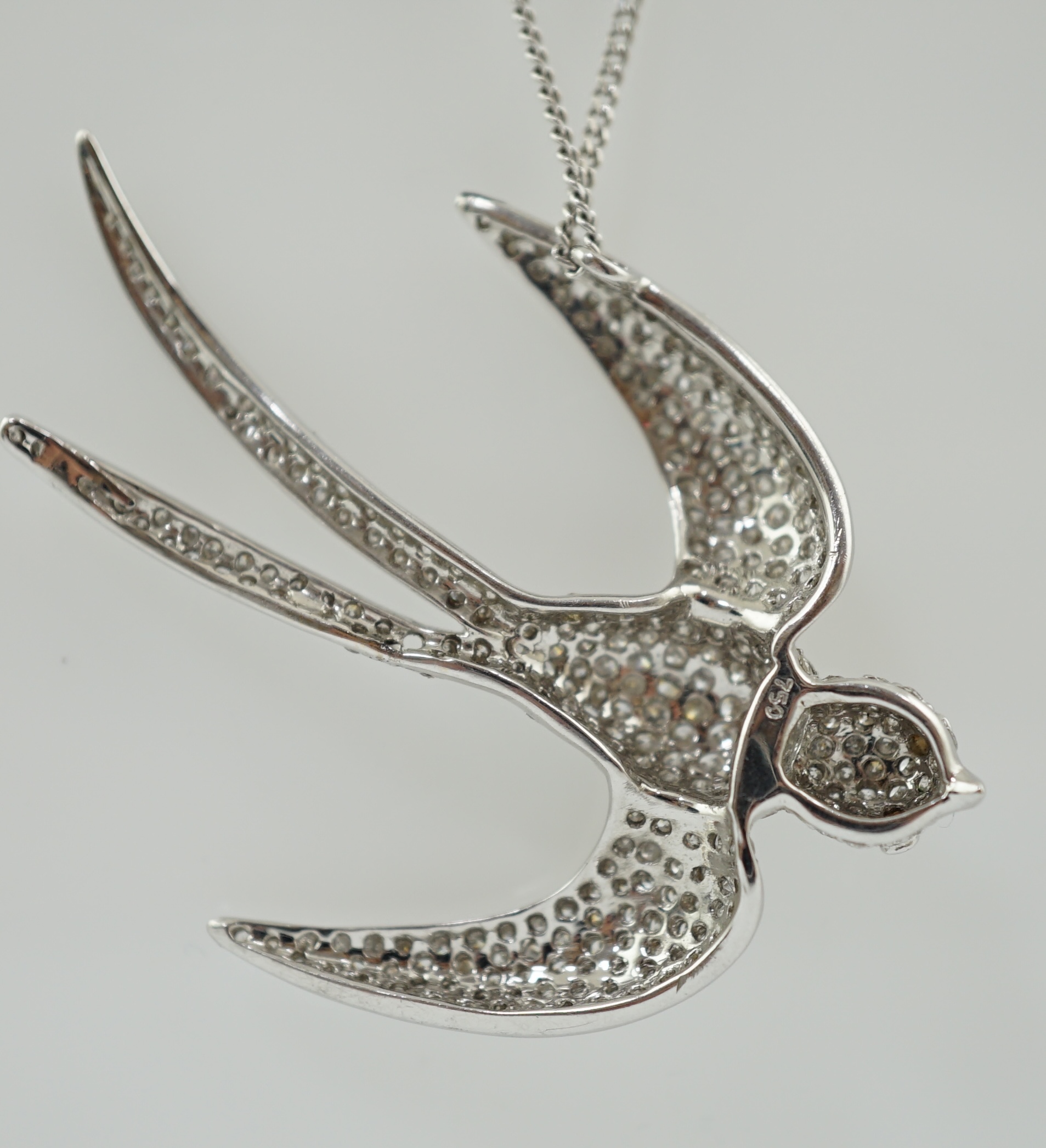 A modern 18k white gold and pavé set diamond pendant, modelled as a swallow, on an 18ct white gold fine link chain
